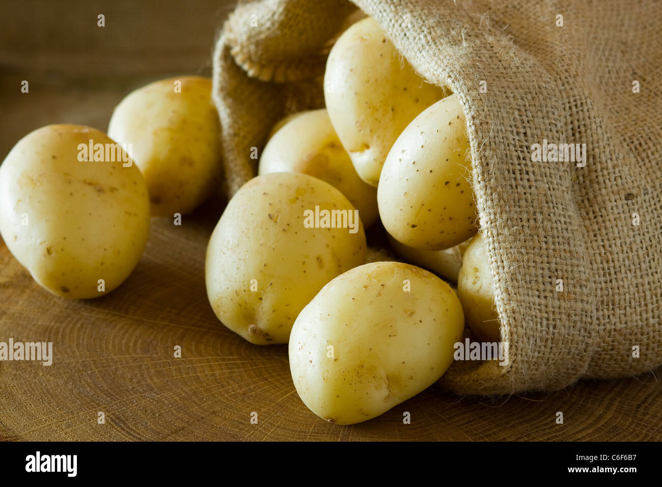 Les pommes de terre en sac de toile brute sur fond de bois Banque D'Images