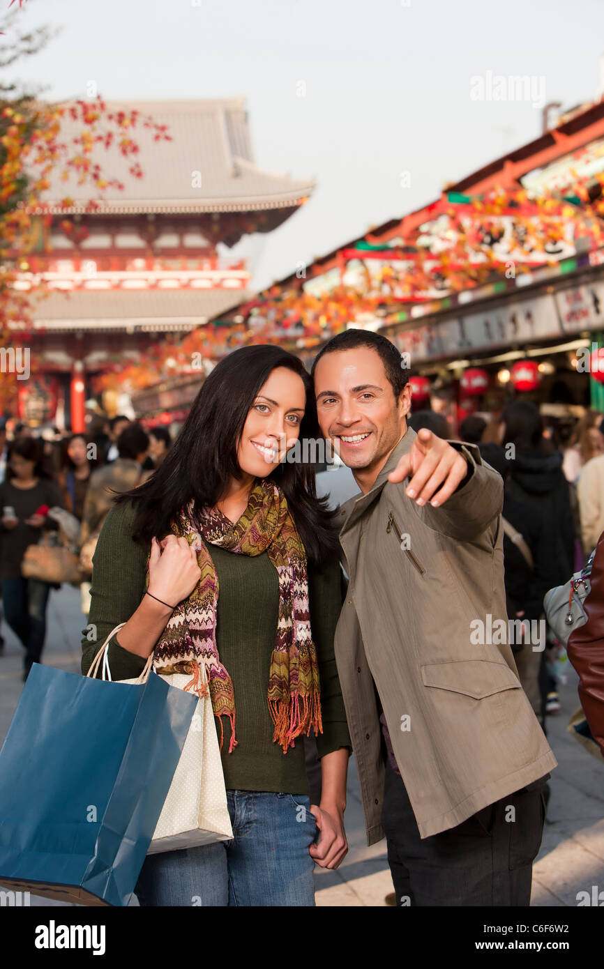 L'homme et de la femme shopping ensemble soulignant les nouvelles boutiques dans centre commercial extérieur. Banque D'Images