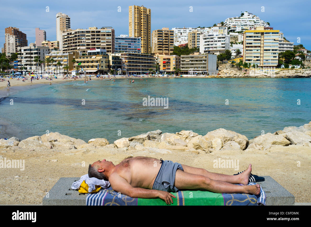 Un homme dort sur un banc de pierre à côté de la plage de Cala Finestrat en Espagne photo par Brian Hickey Banque D'Images