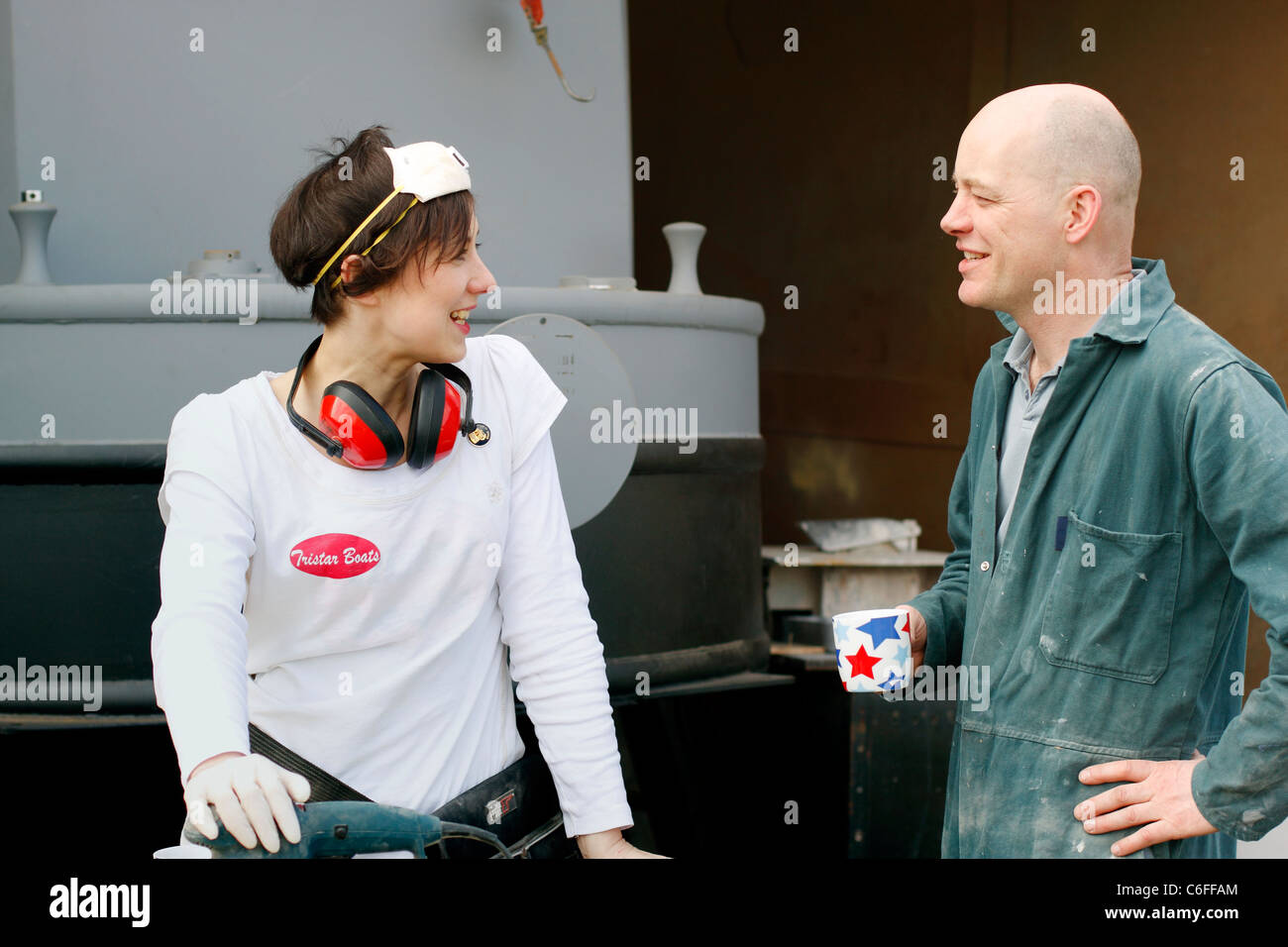 Un homme et une femme chat lors d'une pause, tout en travaillant sur un peu de ponçage de l'intérieur d'un grand classique. Le port de l'EPI. Banque D'Images