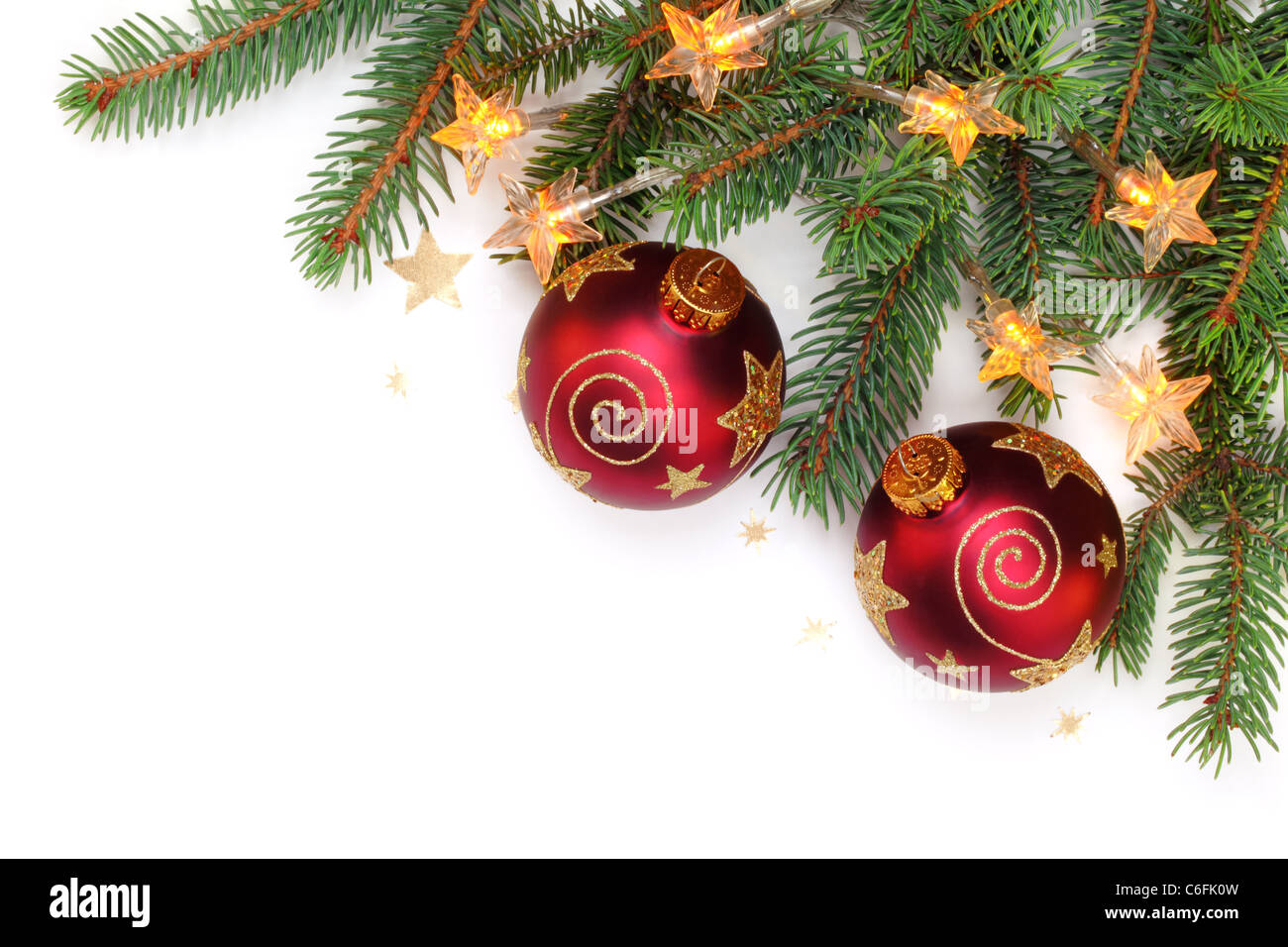 Des branches de pins avec des lumières électriques et balles brillants sur fond blanc Banque D'Images