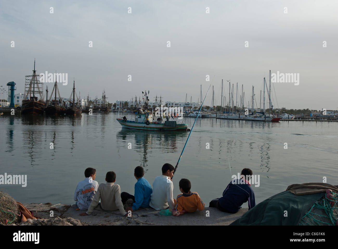 Un groupe de garçons le long du port de pêche de bras de Houmt Souk. Djerba. Tunisie Banque D'Images