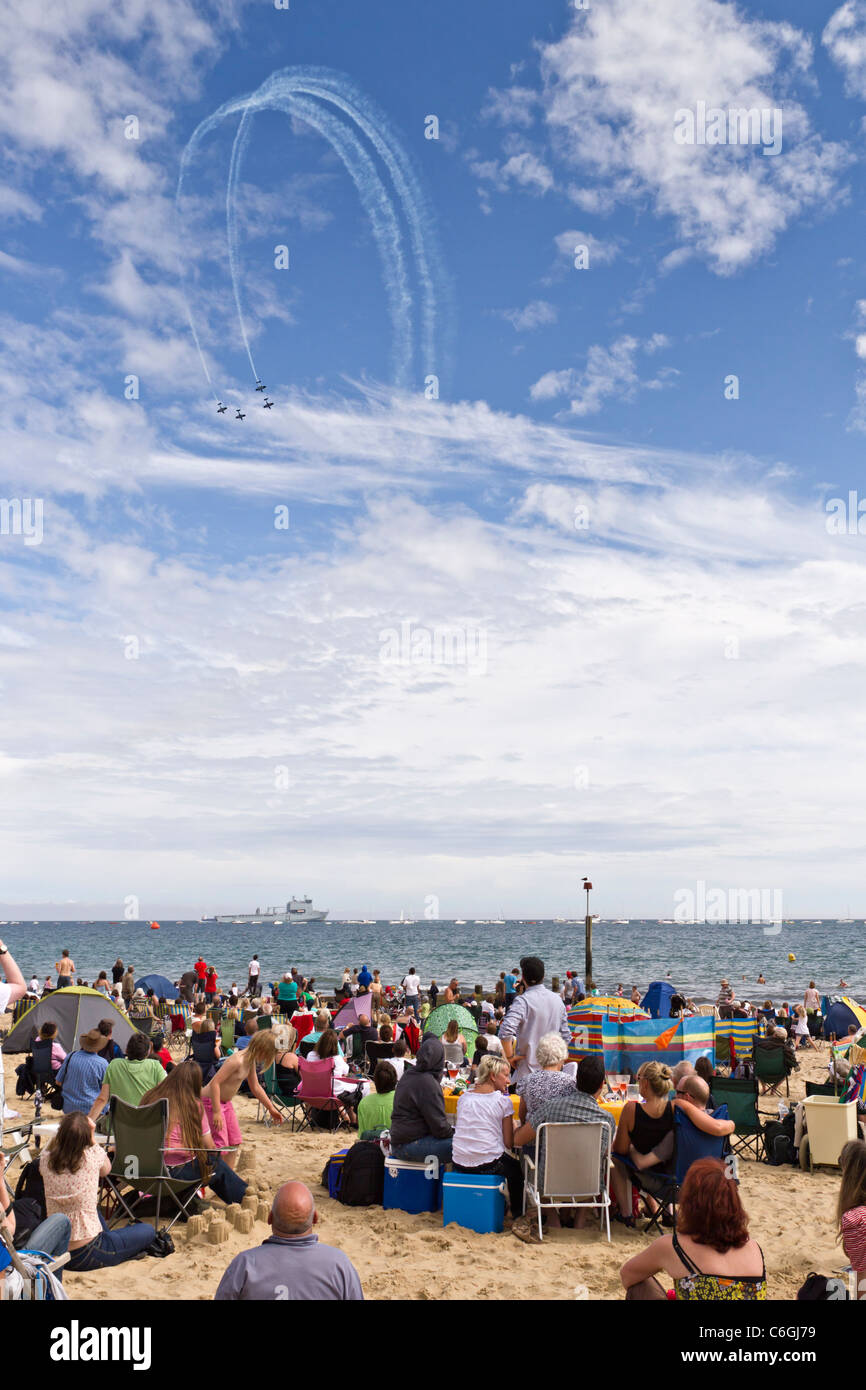 Plage de sable sur les vacanciers appréciant Air Festival Show Display avec 4 avions stunt en formation dans le ciel bleu Banque D'Images