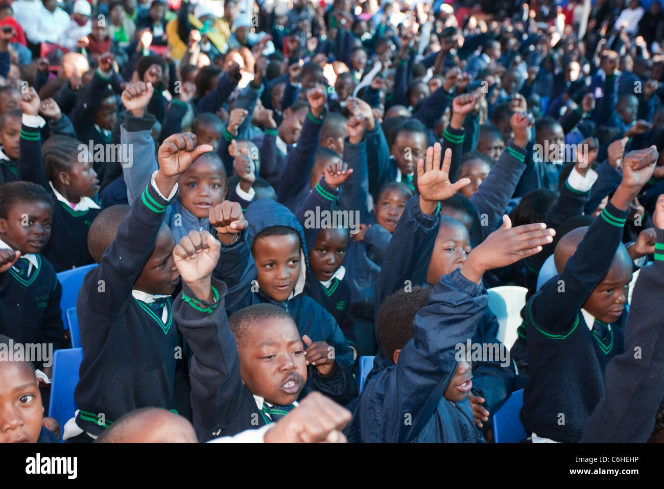 Les enfants d'écoles primaires assemblées ensemble à une école rurale avec des mains ou fist soulevées dans l'expression de l'autonomisation Banque D'Images