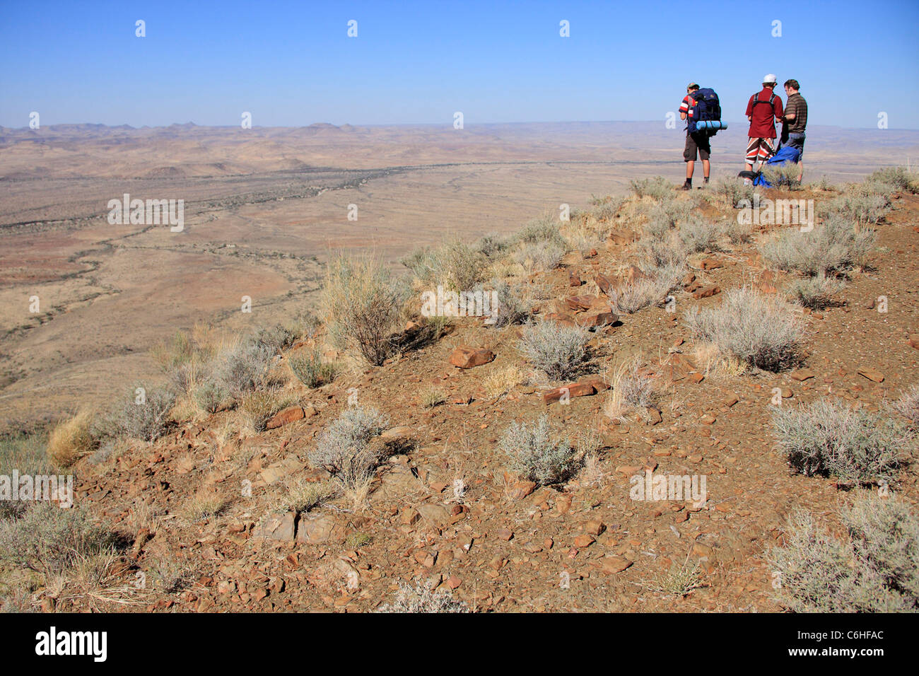 Trois randonneurs à la recherche sur la vallée ci-dessous de high point Banque D'Images
