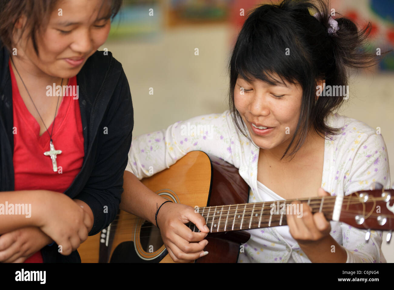 Filles thai chantant et jouant de la guitare dans l'école de rééducation, Chiang Rai, Thaïlande Banque D'Images
