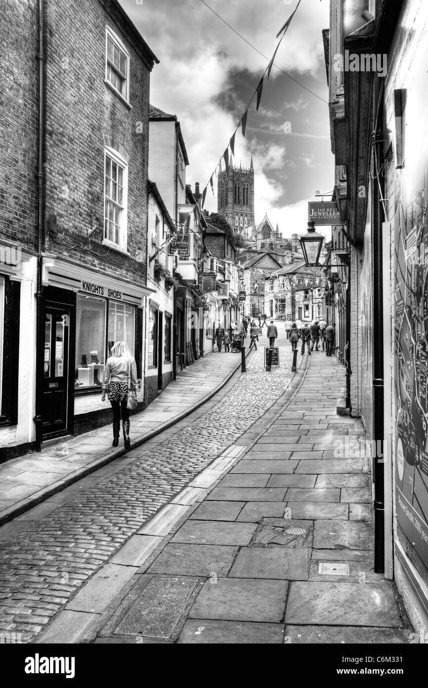 La ville de Lincoln, Lincolnshire regardant les boutiques jusqu'abrupte route pavée avec les touristes et les acheteurs en haut de la cathédrale Banque D'Images
