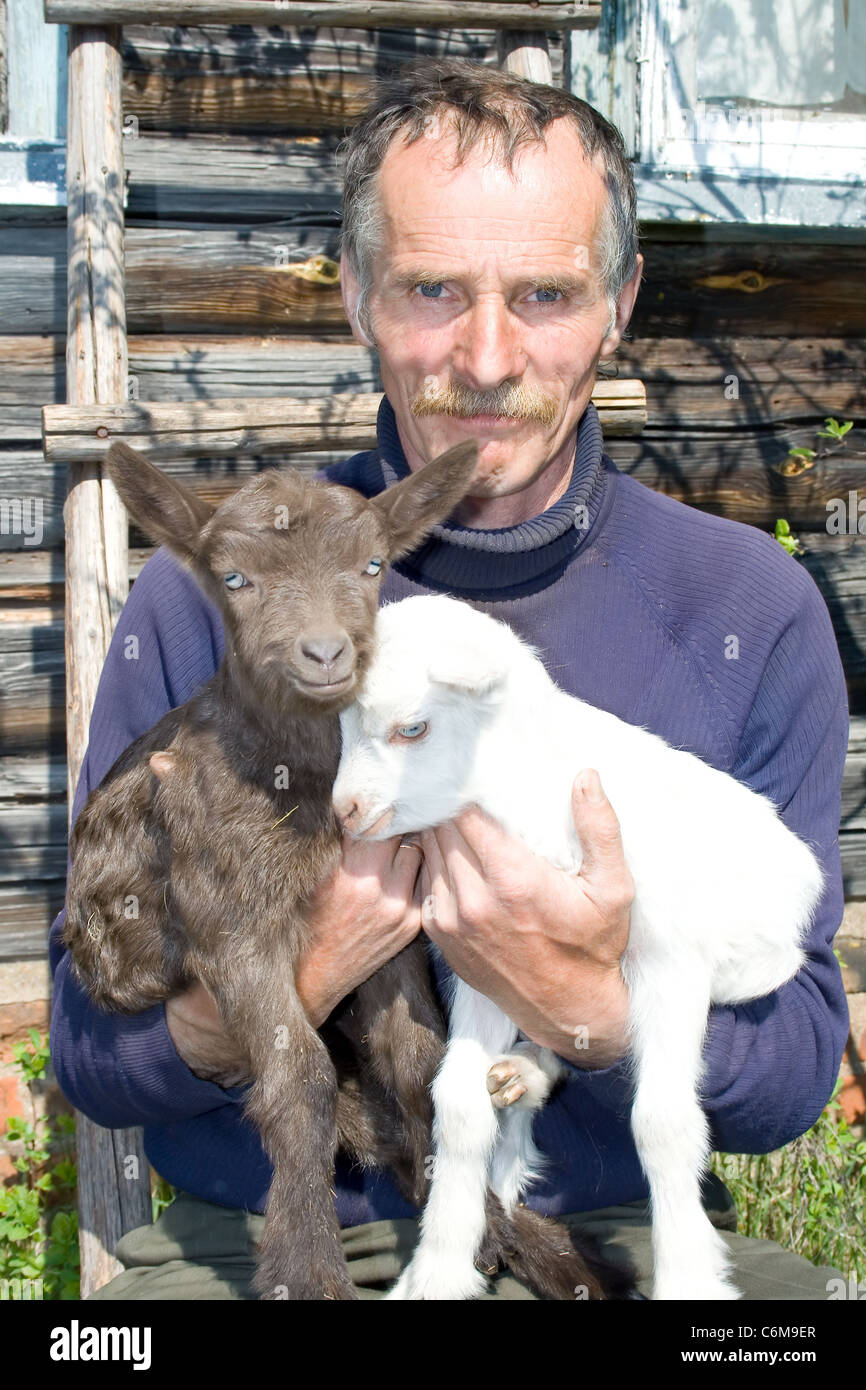 Portrait d'agriculteur avec de jeunes chèvres. Banque D'Images