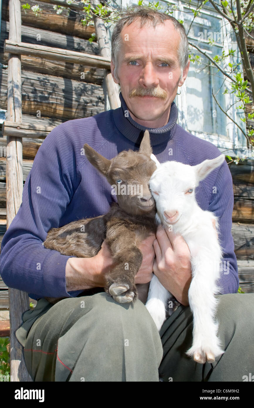 Portrait d'agriculteur avec de jeunes chèvres. Banque D'Images