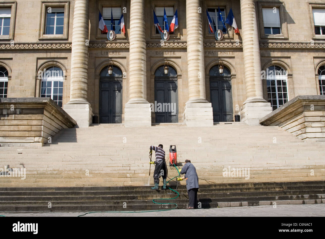 Deux agents d'entretien en vertu de l'inscription 'Liberte, Egalite, Fraternite" au Palais de Justice Banque D'Images