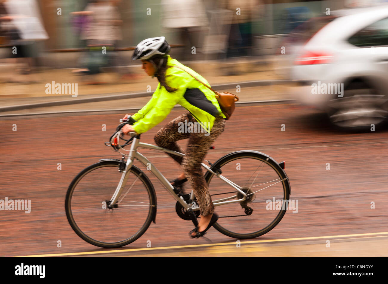 Une femme à vélo à travers la ville avec flou délibéré à Norwich , Norfolk , Angleterre , Angleterre , Royaume-Uni Banque D'Images