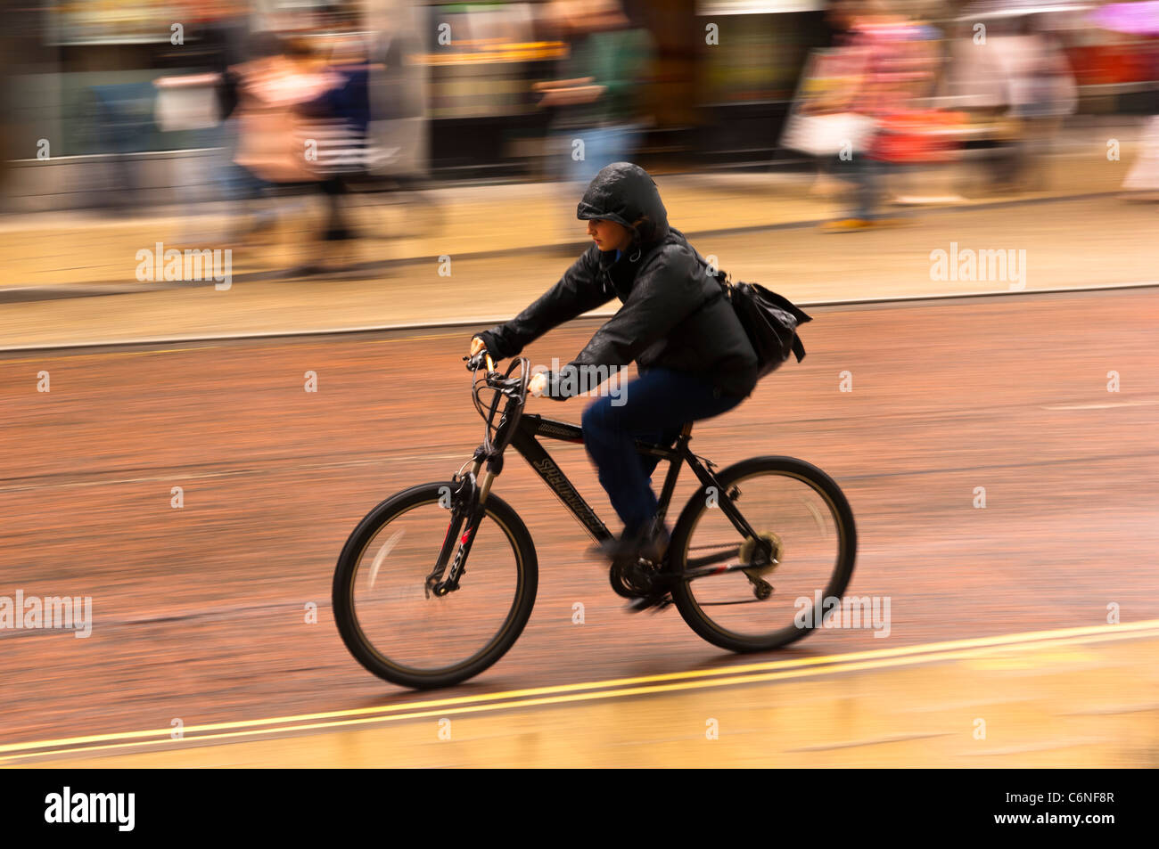 Une femme à vélo à travers la ville avec flou délibéré à Norwich , Norfolk , Angleterre , Angleterre , Royaume-Uni Banque D'Images