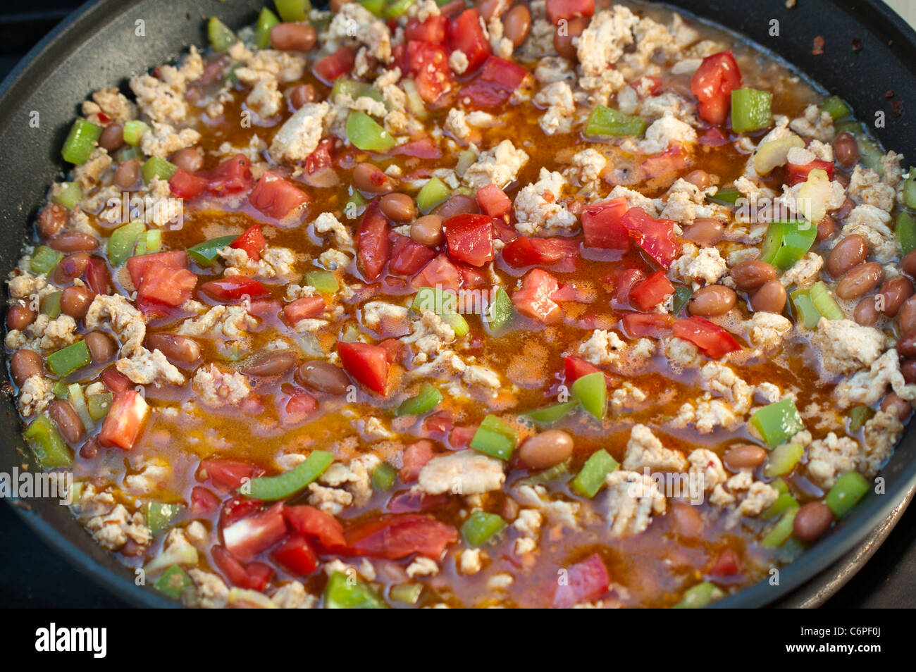 Le Chili fait maison avec la dinde, les haricots pinto, poivron vert et Tomates mijoter dans une casserole anti-adhérente Banque D'Images