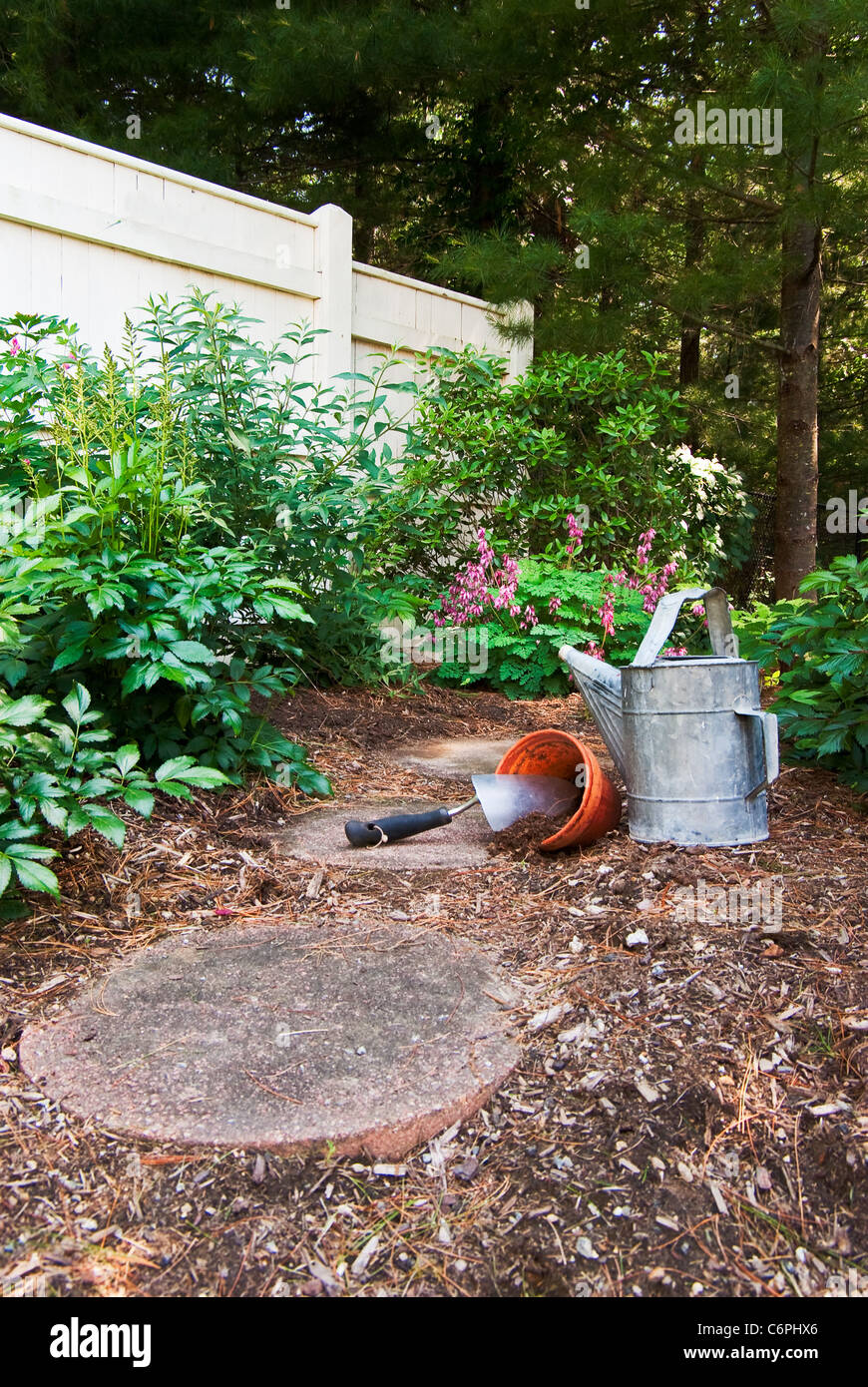 Un vieil arrosoir est assis à côté d'une truelle et pot en argile qui sont prêts pour les fleurs Banque D'Images