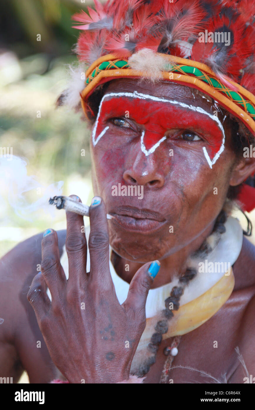 Tribeswoman de Papouasie-Nouvelle-Guinée, de fumer une cigarette à partir de laminés newspaper Banque D'Images