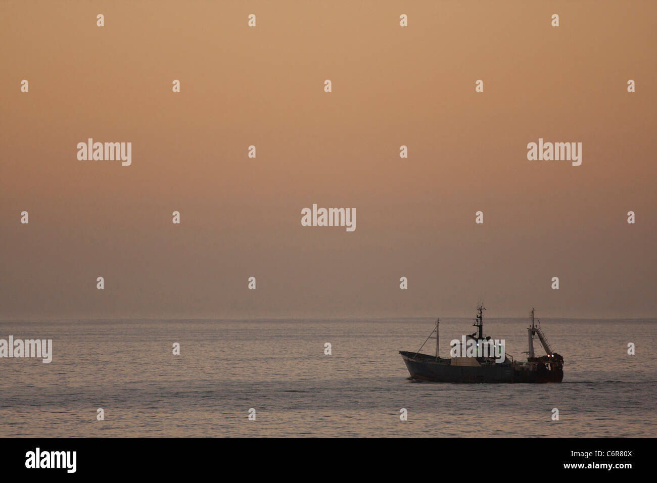 Bateau de pêche commerciale sur l'océan au lever du soleil Banque D'Images