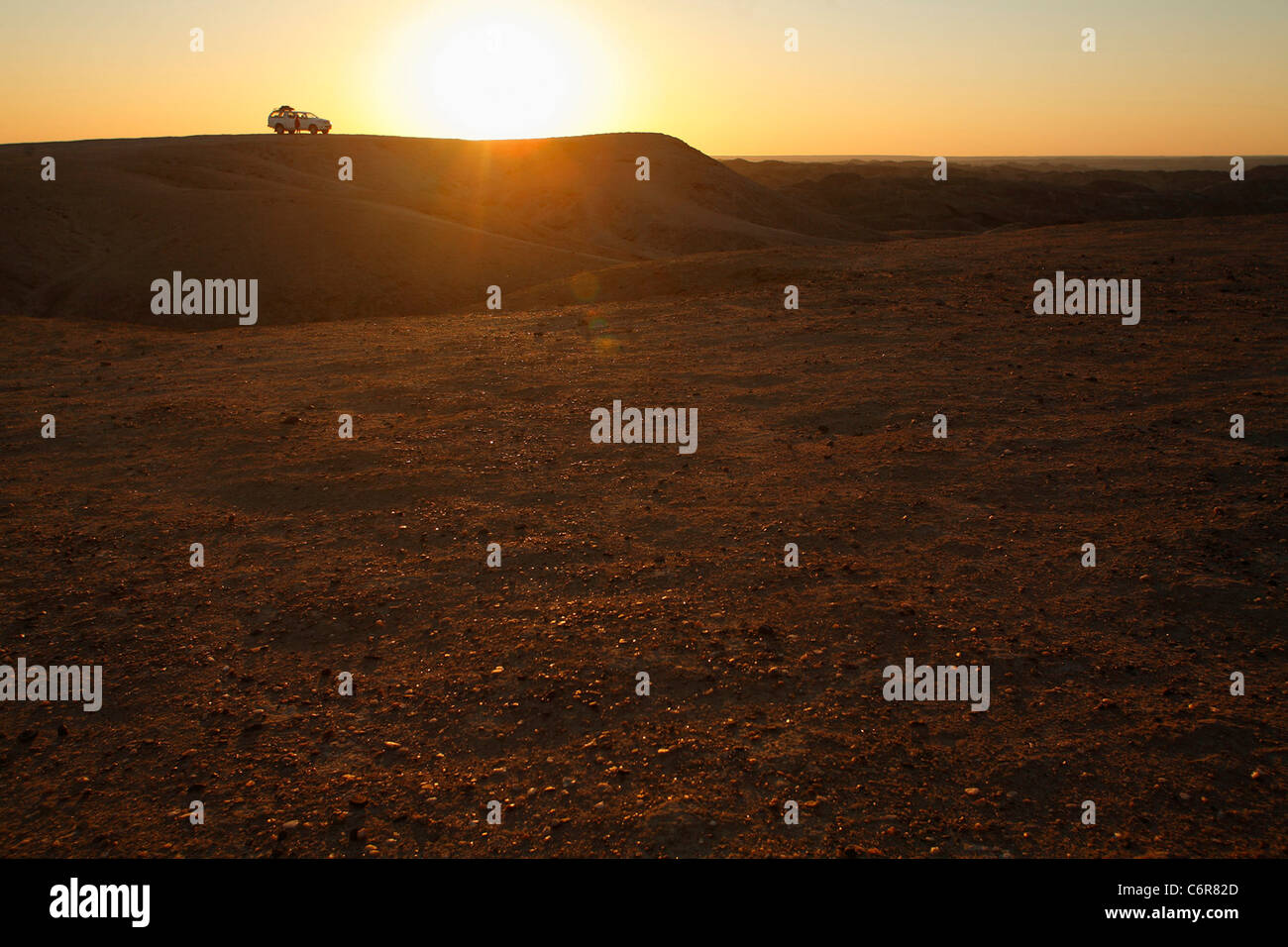 Paysage désertique avec véhicule isolé sur une crête dans la distance au crépuscule Banque D'Images