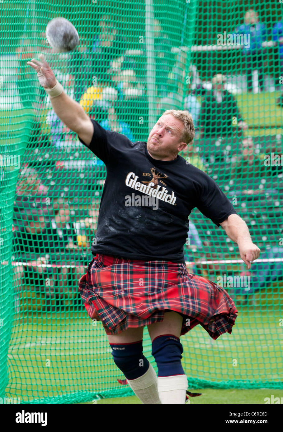 Une lourde dans un kilt en concurrence dans le cas de jets de pierre lors de la collecte en Ecosse Highland Braemar Banque D'Images