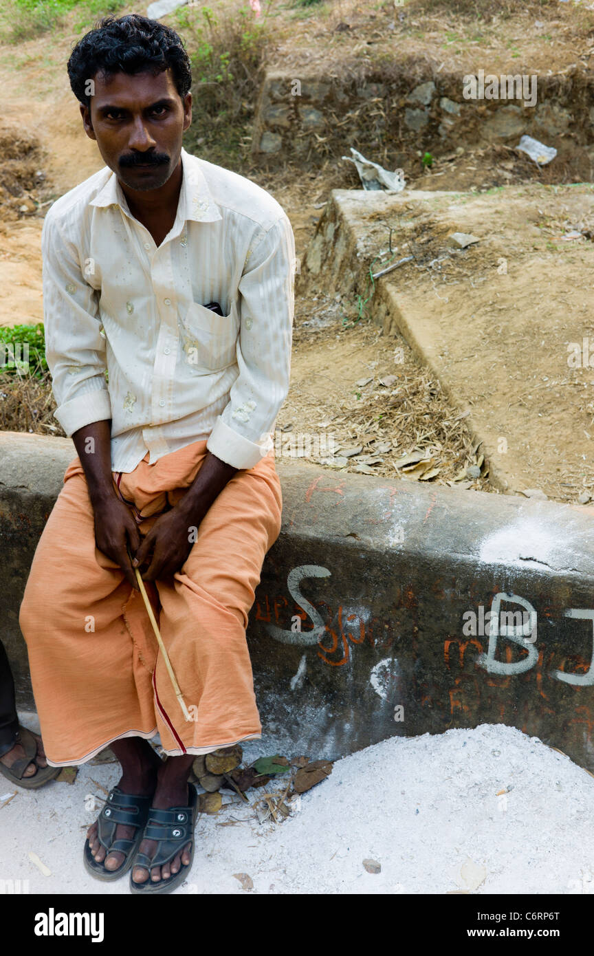 Un homme de détente à un festival religieux au kerala porter un kilt mundu orange. Banque D'Images