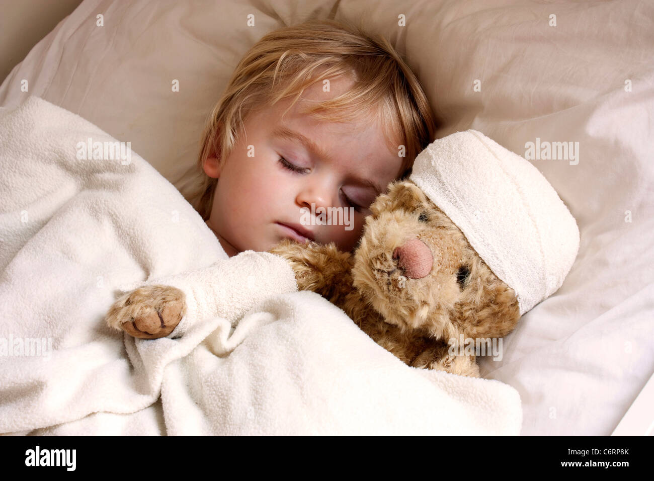Garçon et nounours au lit, avec teddy bandé Banque D'Images