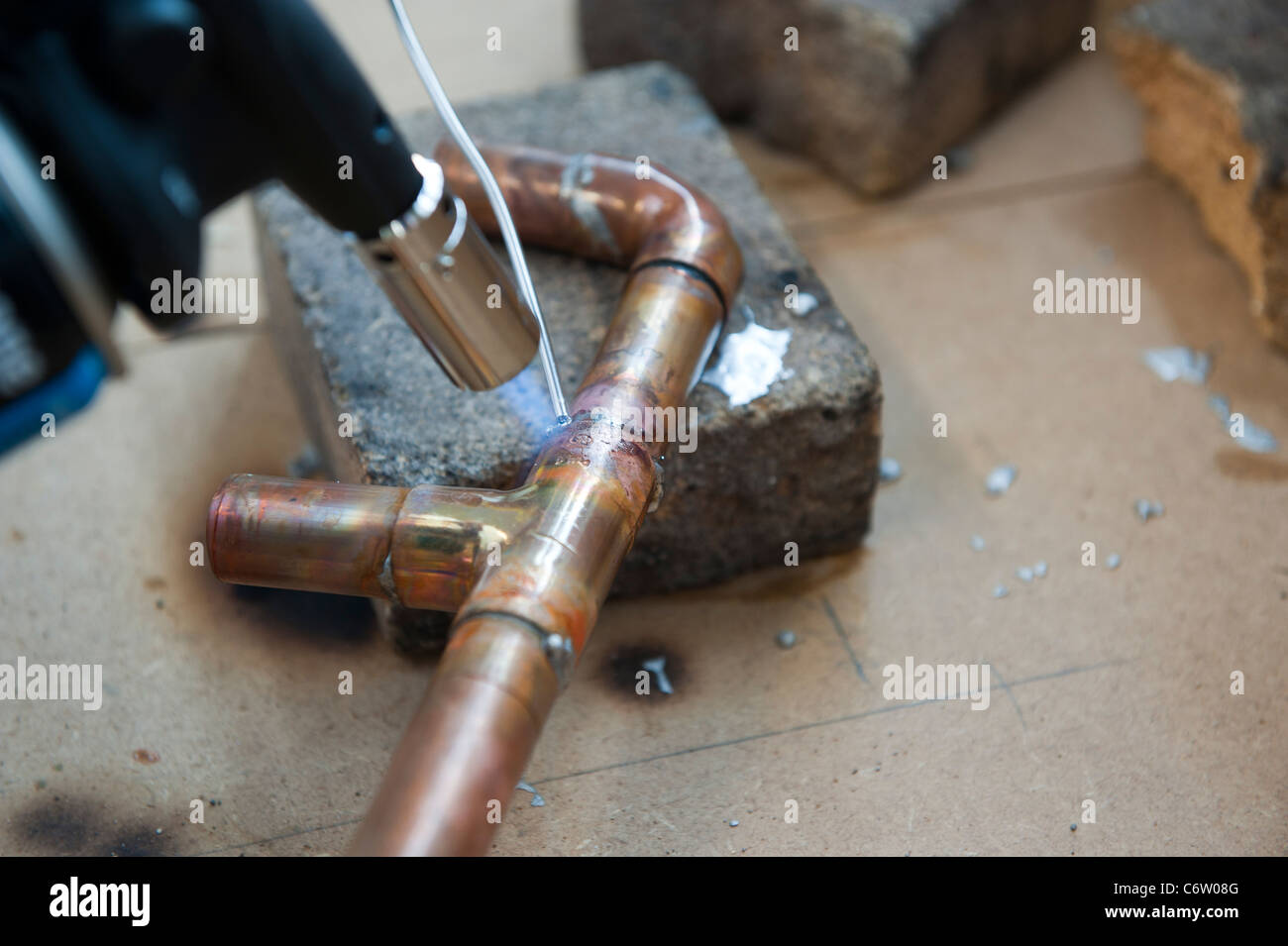 Un chalumeau réchauffe un tuyau de chauffage en cuivre pour une utilisation dans la plomberie. Banque D'Images