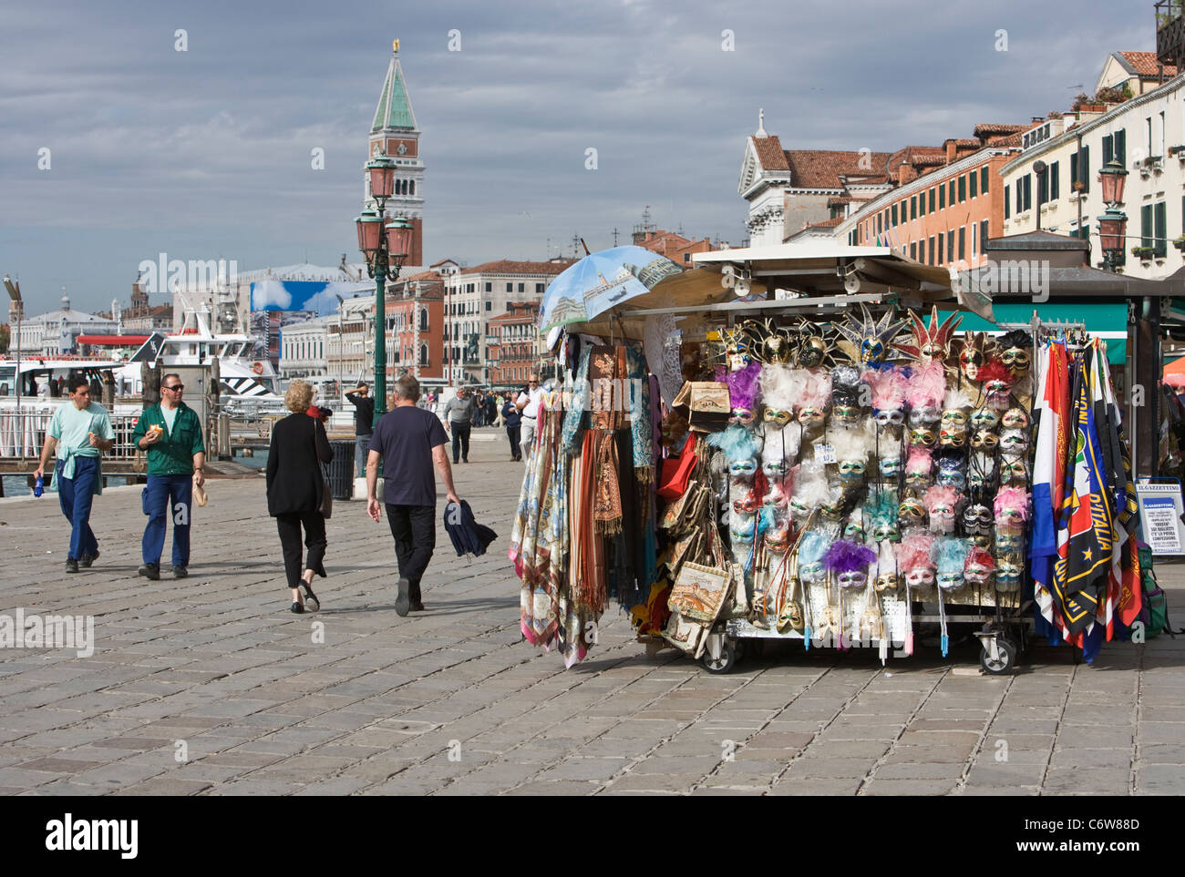 Les touristes se promener passé un stand de souvenirs sur la promenade le long du Canale di San Marco à Venise Banque D'Images