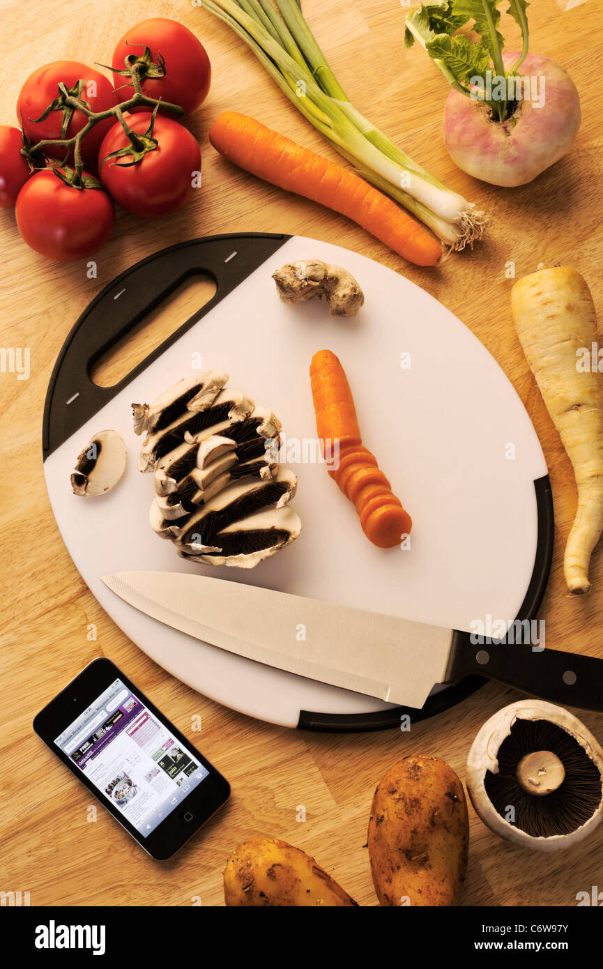 Planche à découper en plastique au cours de la préparation des aliments avec fiche sur 'Apple' écran d'iPod touch. Banque D'Images