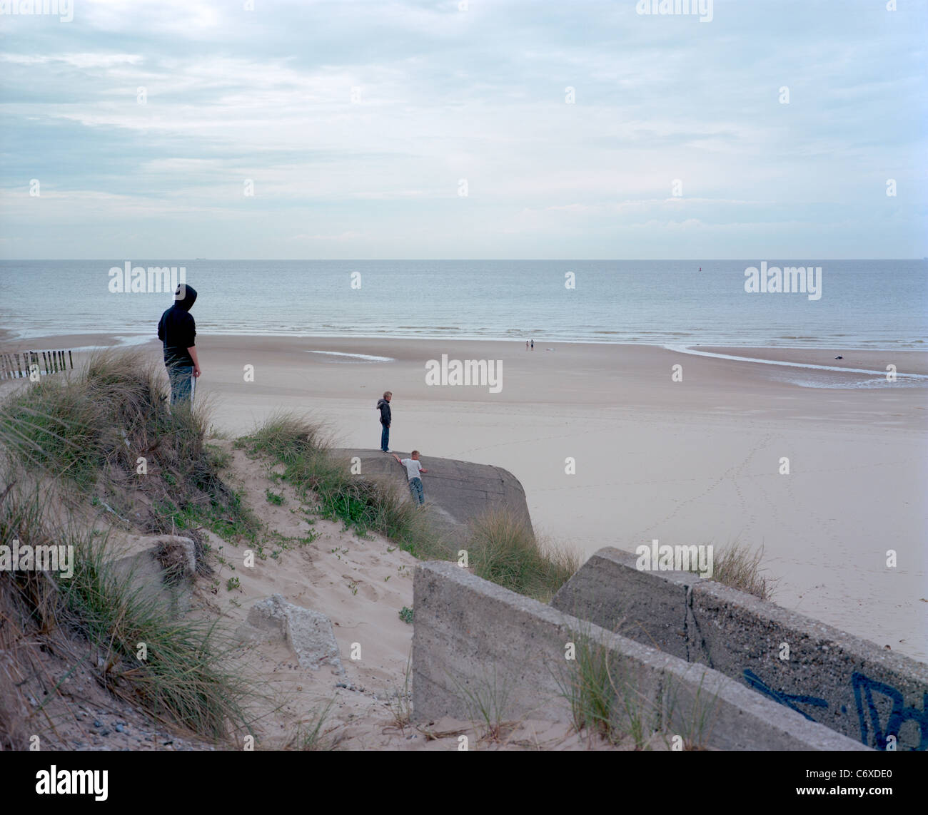 Trois personnes errant sur les ruines de fortifications dans les dunes de sable. Banque D'Images