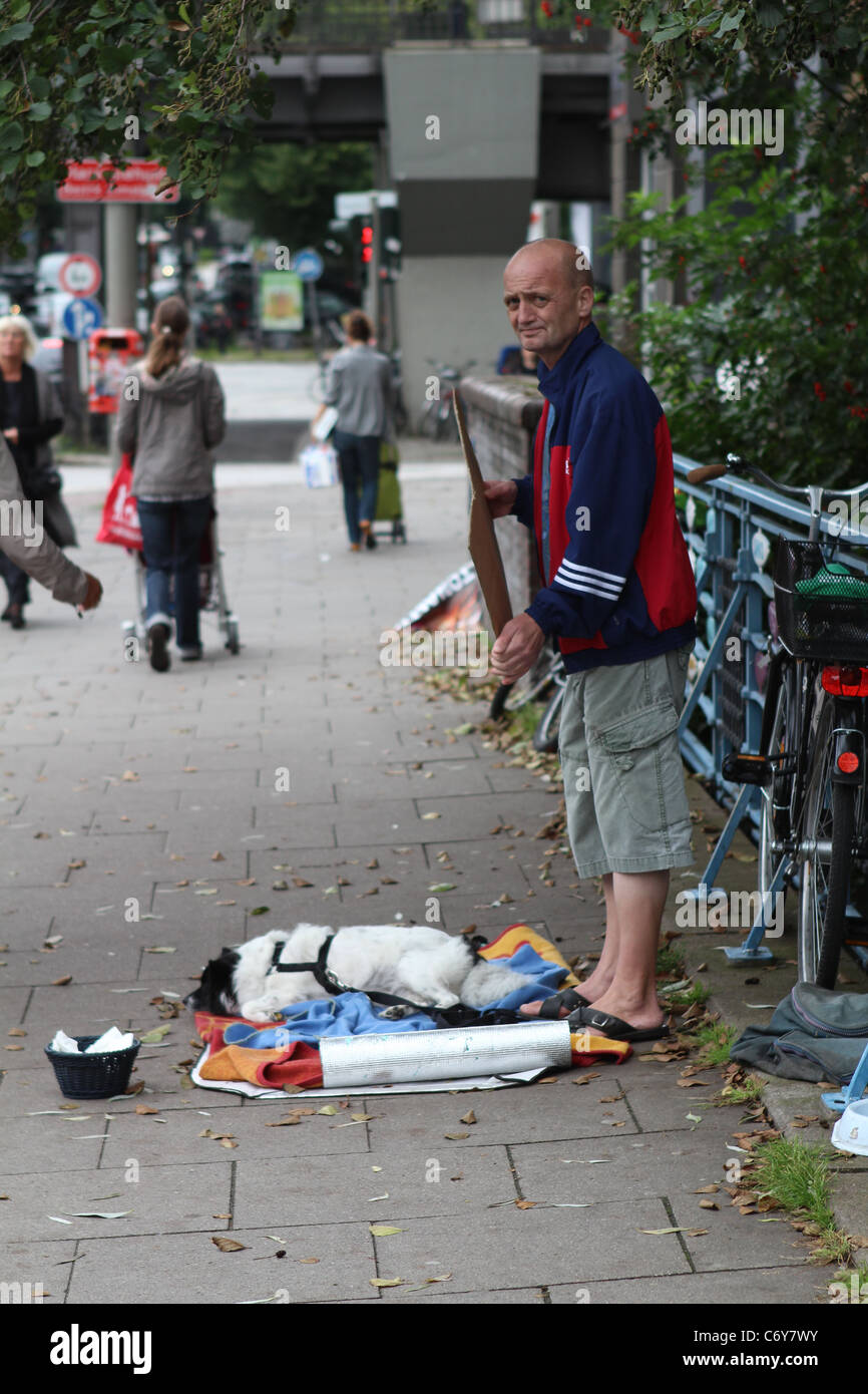 Mendiant sur chaussée occupé avec son chien pour demander de l'argent Banque D'Images