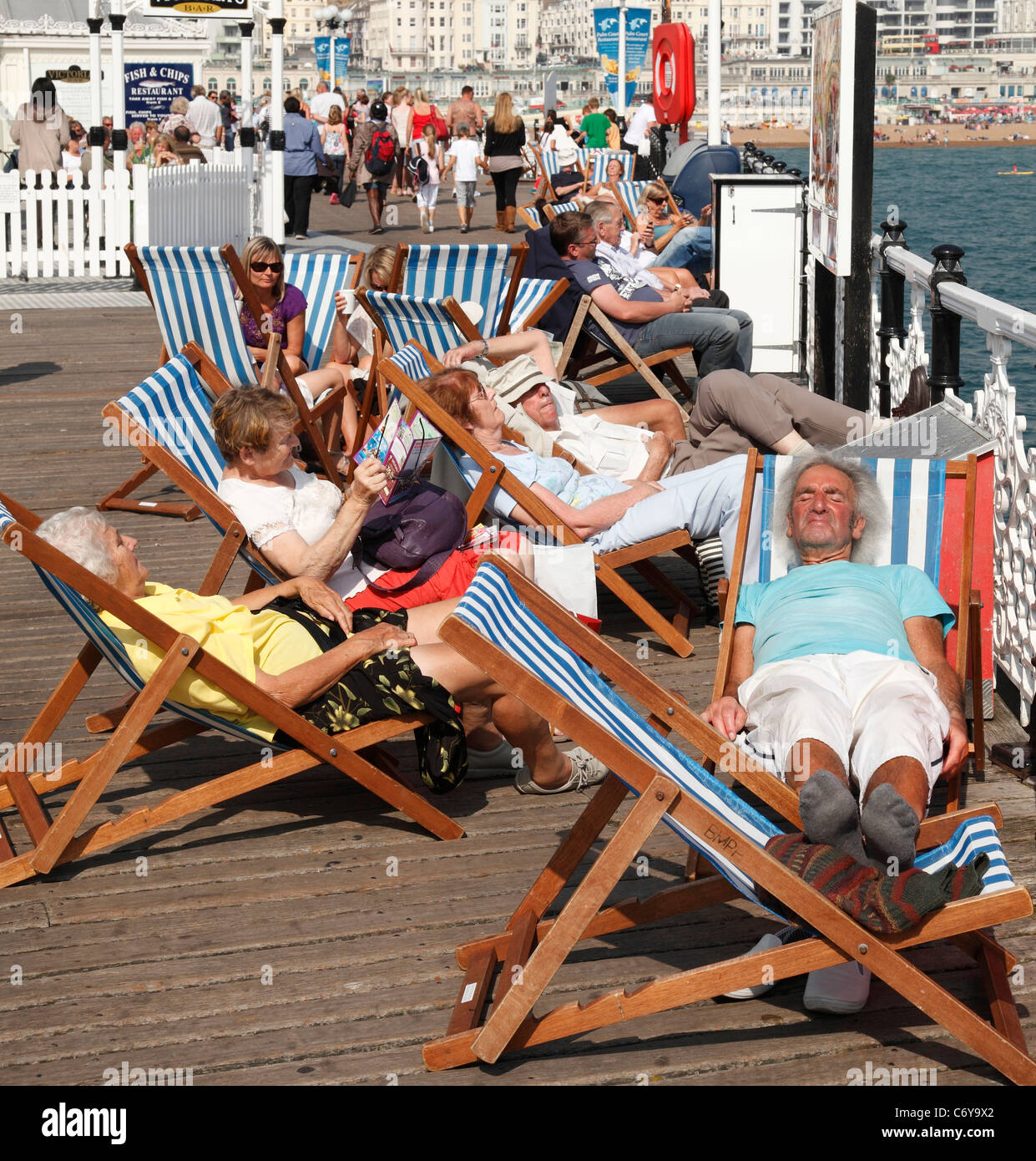 Les vacanciers en vous relaxant dans des chaises longues sur la jetée de Brighton, Brighton, Angleterre, Royaume-Uni Banque D'Images