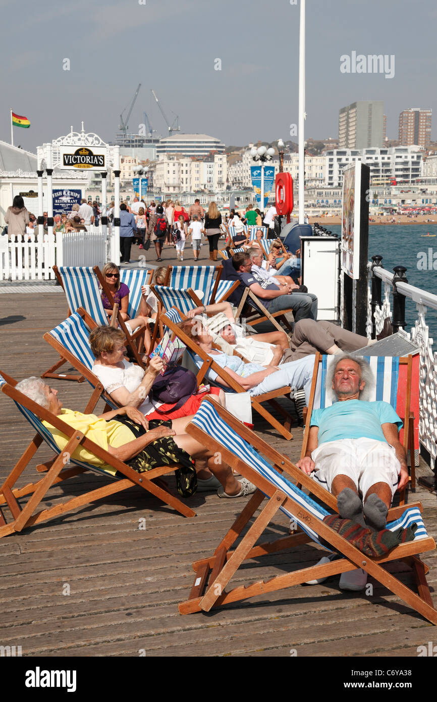 Les vacanciers en vous relaxant dans des chaises longues sur la jetée de Brighton, Brighton, Angleterre, Royaume-Uni Banque D'Images