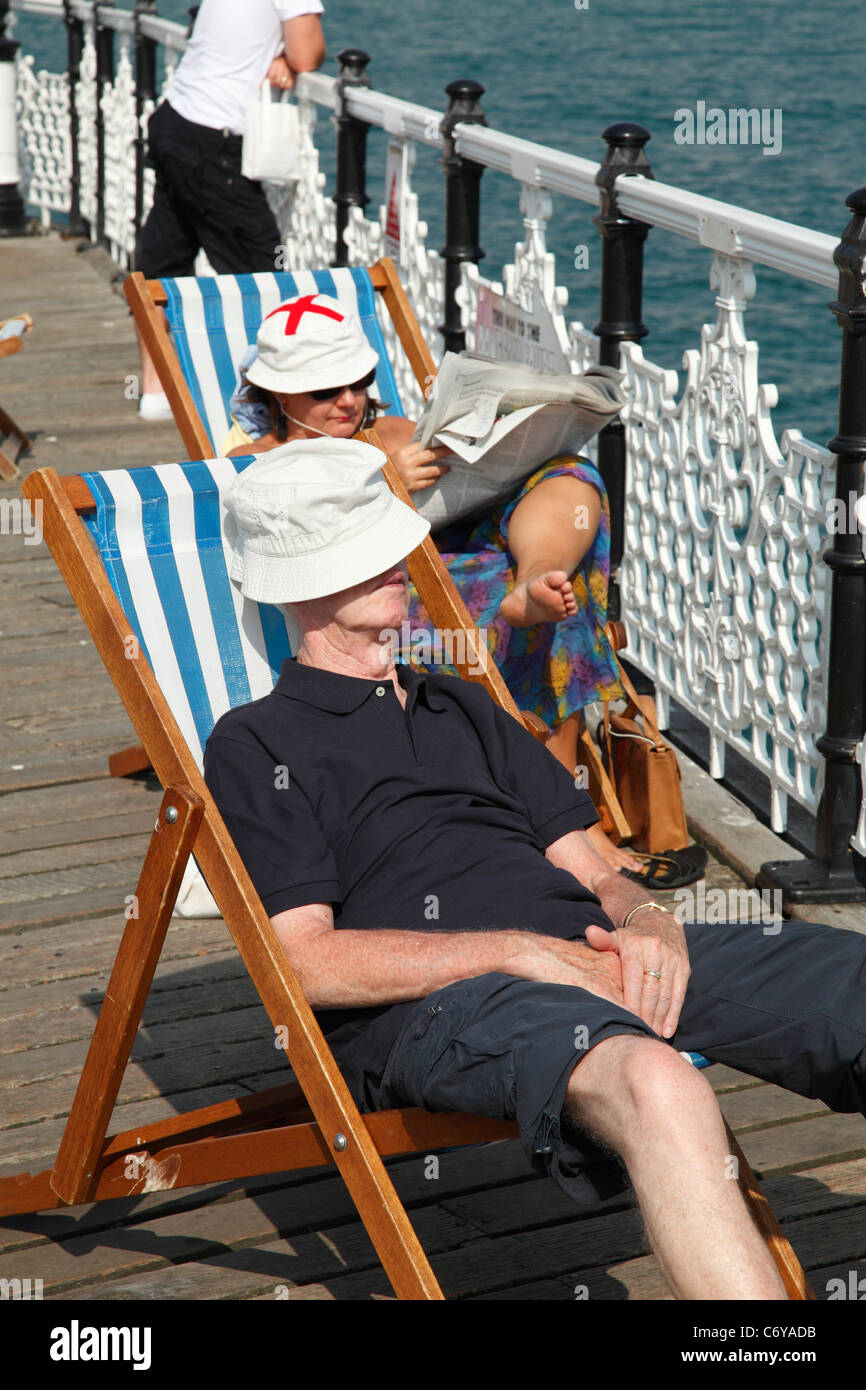 Les gens vous relaxant dans des chaises longues sur la jetée de Brighton, Brighton, Angleterre, Royaume-Uni Banque D'Images