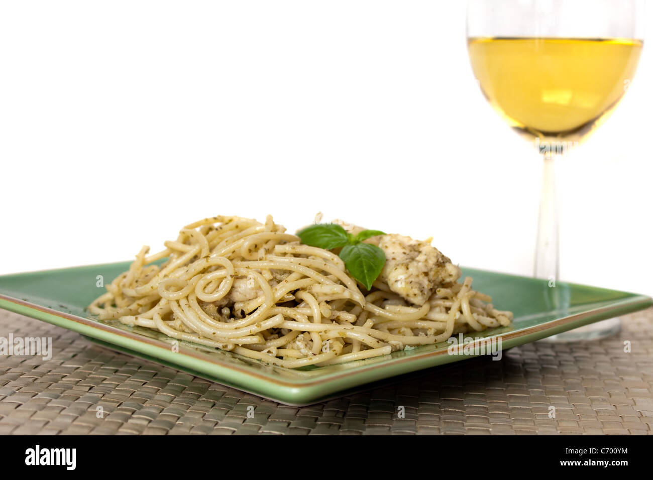 Un plat de spaghetti à l'ail et le poulet au pesto avec un verre de vin blanc. Profondeur de champ. Banque D'Images