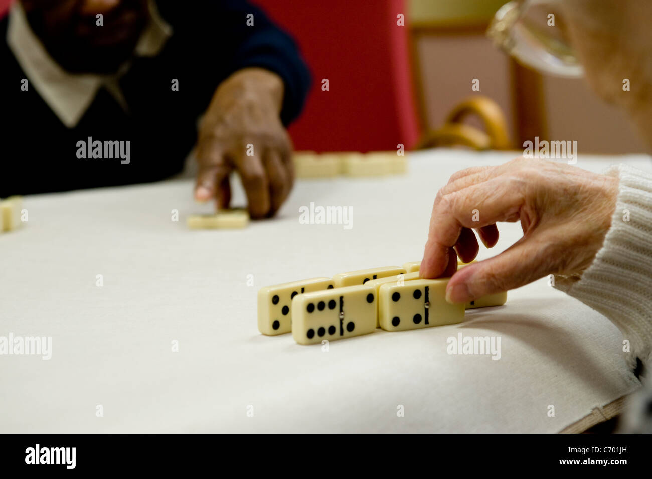 Vieux gens jouer aux dominos dans un centre de jour pour les personnes âgées Banque D'Images