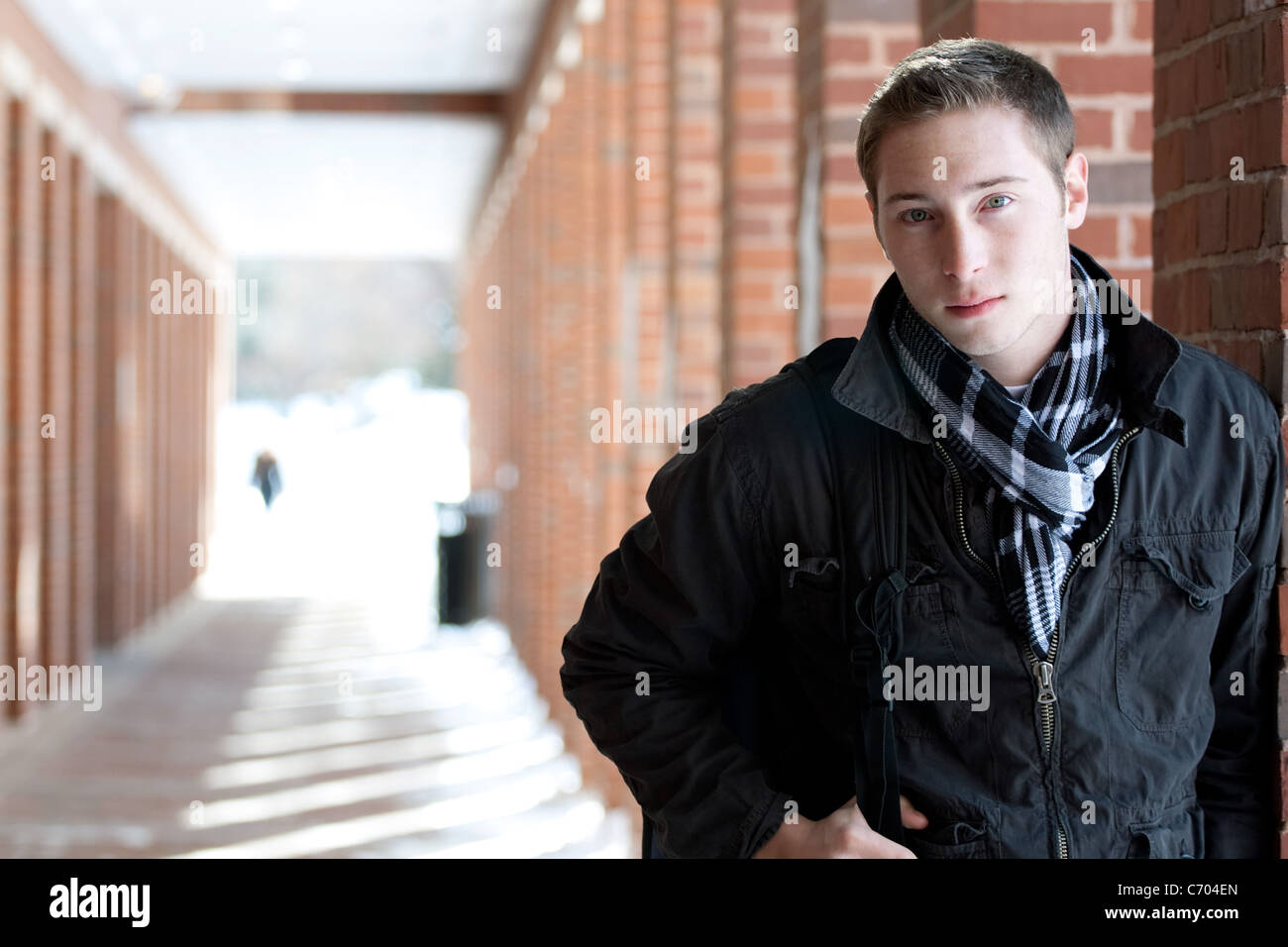 Un portrait d'un jeune homme debout dans un couloir en plein air avec son sac à dos. Banque D'Images