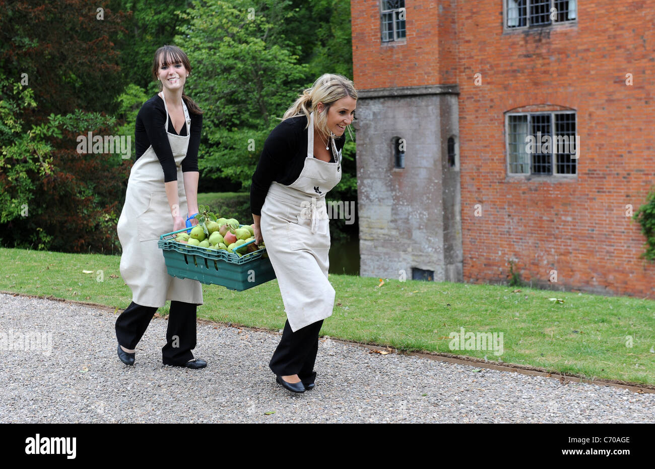 Deux jeunes femmes portant la récolte des pommes England Uk Banque D'Images