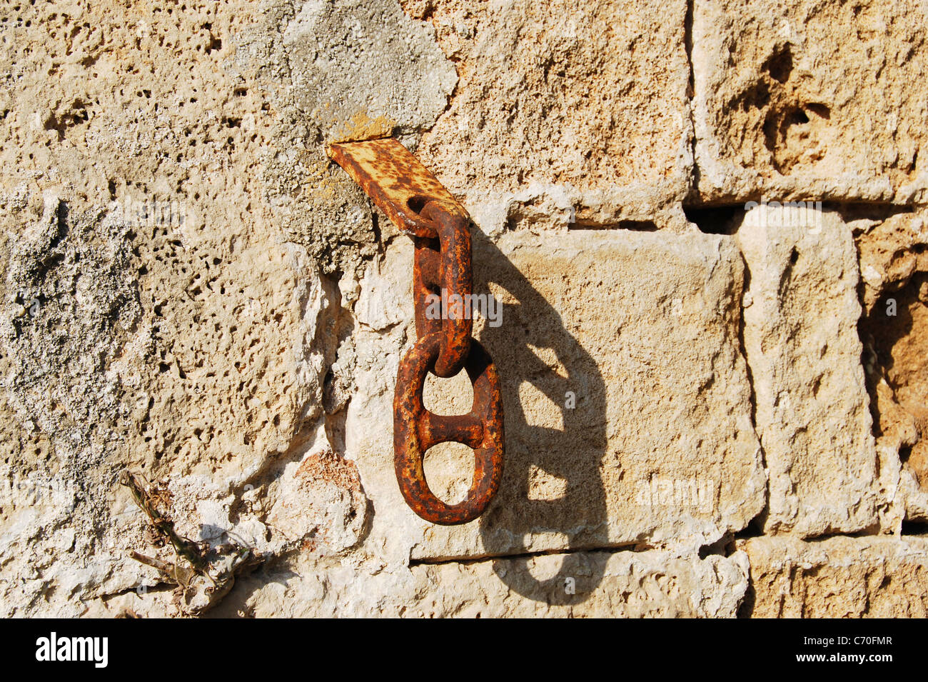 Fragment de l'ancien mur de pierre avec l'ancienne chaîne rouillée. Banque D'Images