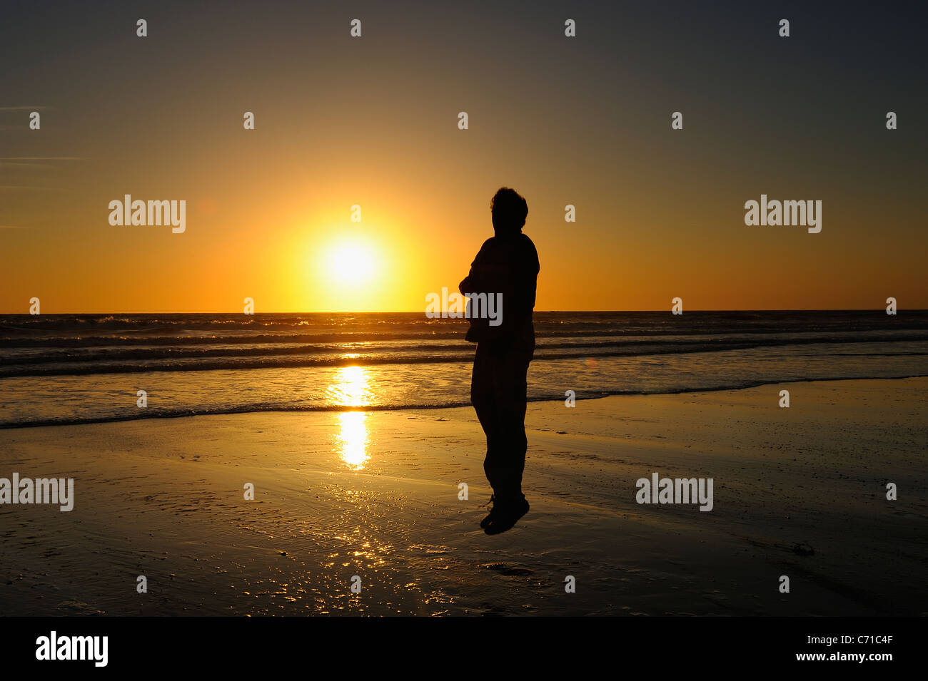 Man sur la plage pendant un coucher de soleil jaune sur l'océan Atlantique depuis la Côte Sauvage, Charente Maritime, France Banque D'Images