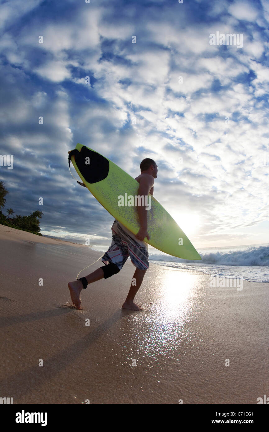 Jeune homme marchant à la surf à Rocky Point, sur la côte nord d'Oahu, Hawaii. Banque D'Images