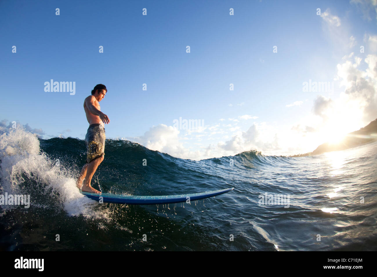 Un jeune homme le surf dans la lumière à Monster Mush, sur la côte nord d'Oahu, Hawaii. Banque D'Images