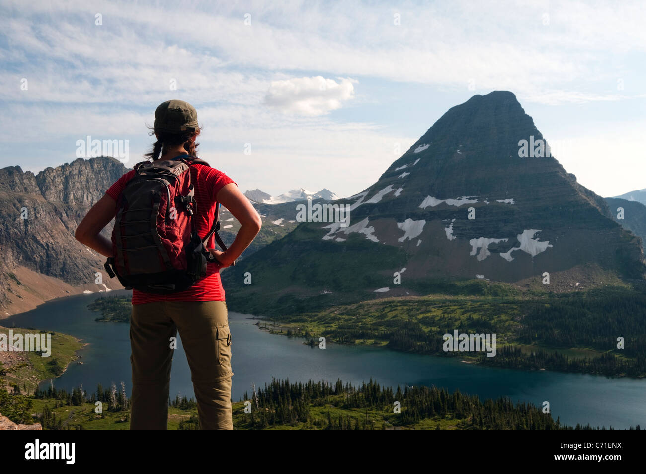 Une jeune femme hiker donne sur le lac caché et l'ours dans la montagne Hat le Glacier National Park, Montana. Banque D'Images