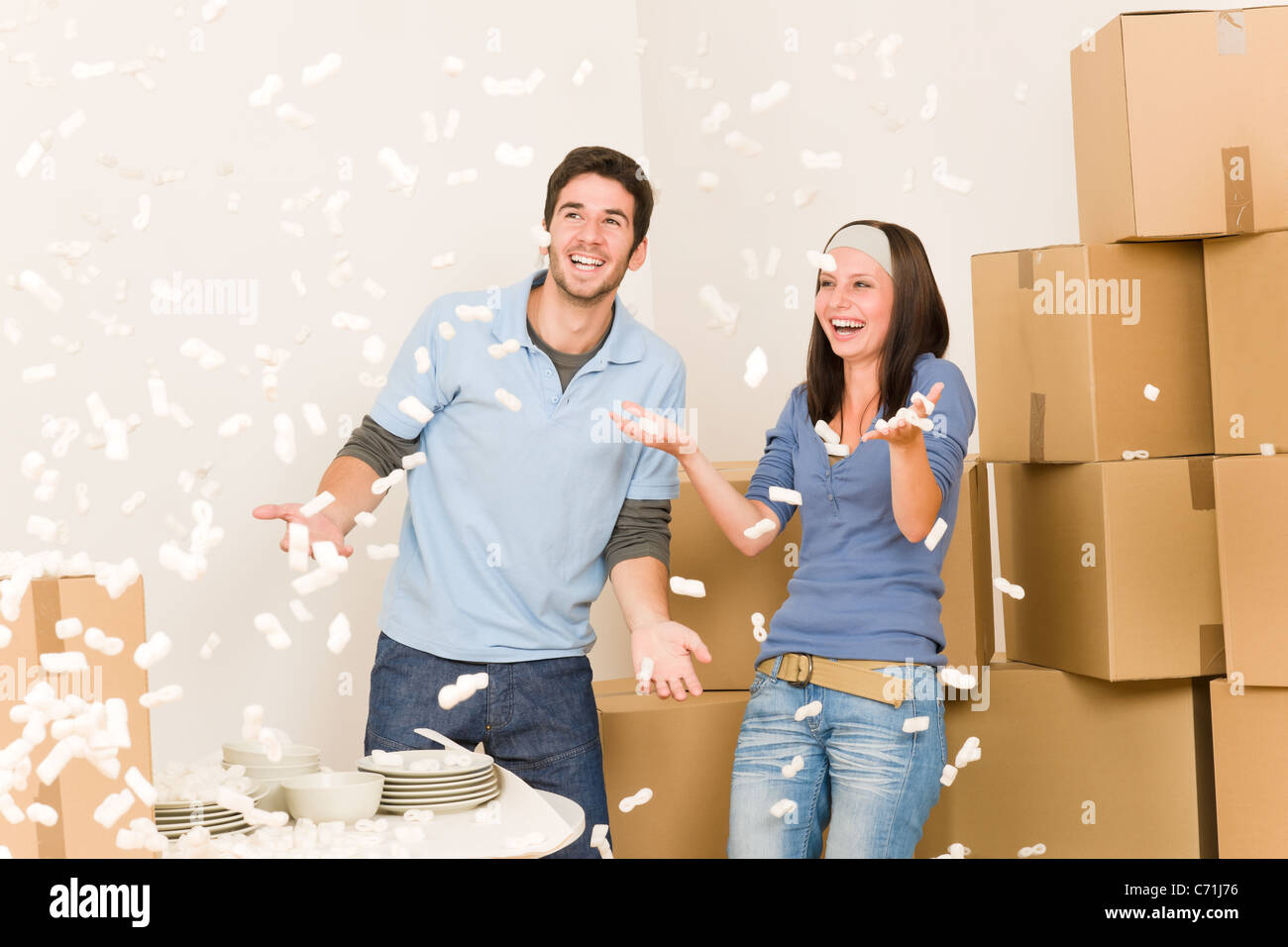 Déménagement Accueil young cheerful couple jeter de polystyrène expansé unpacking boxes Banque D'Images