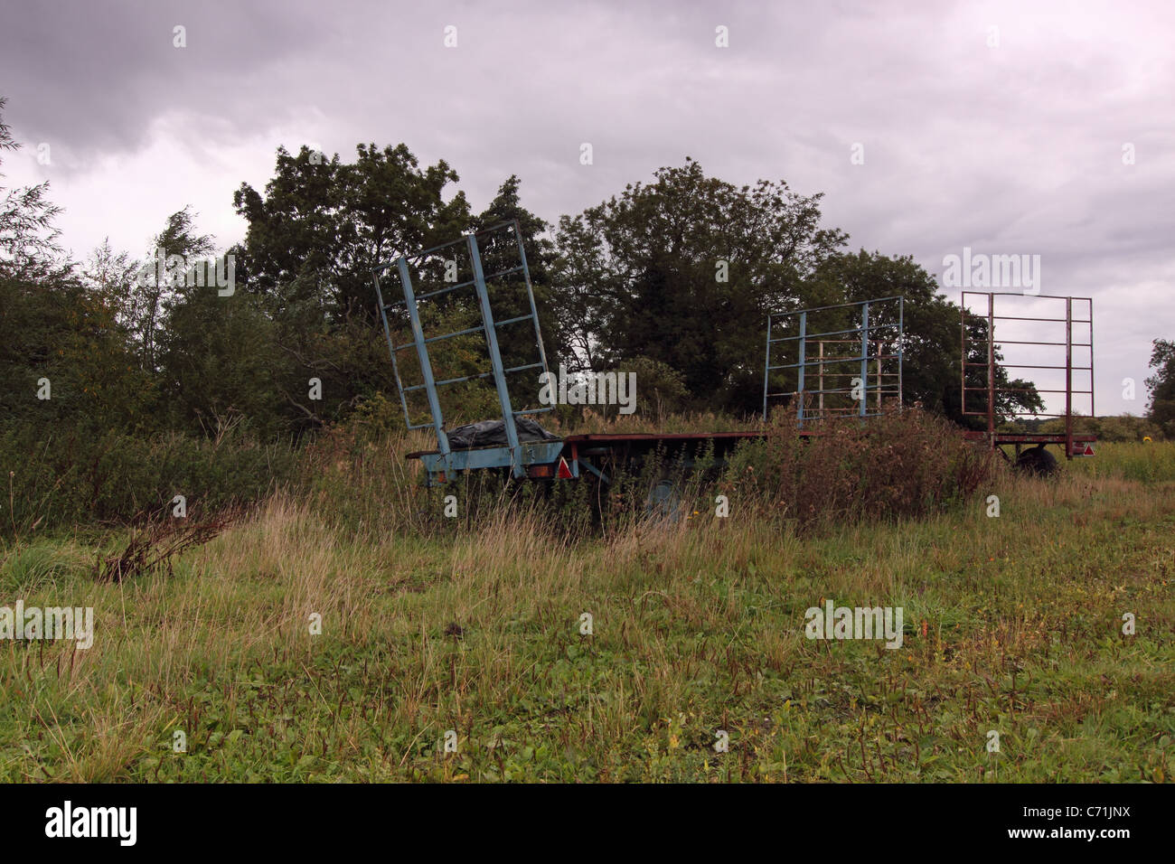 Vieux envahis par les machines agricoles se trouvant dans un champ à l'abandon de déchets paysage oublié cassé rouille uk angleterre remorque agricole Banque D'Images