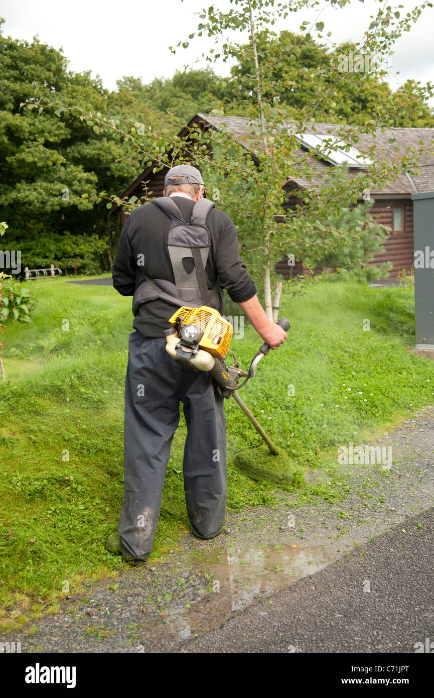 Un ouvrier qui a coupé de l'herbe avec un strimmer Bluestone essence au Parc National de pembrokeshire, resort West Wales UK Banque D'Images