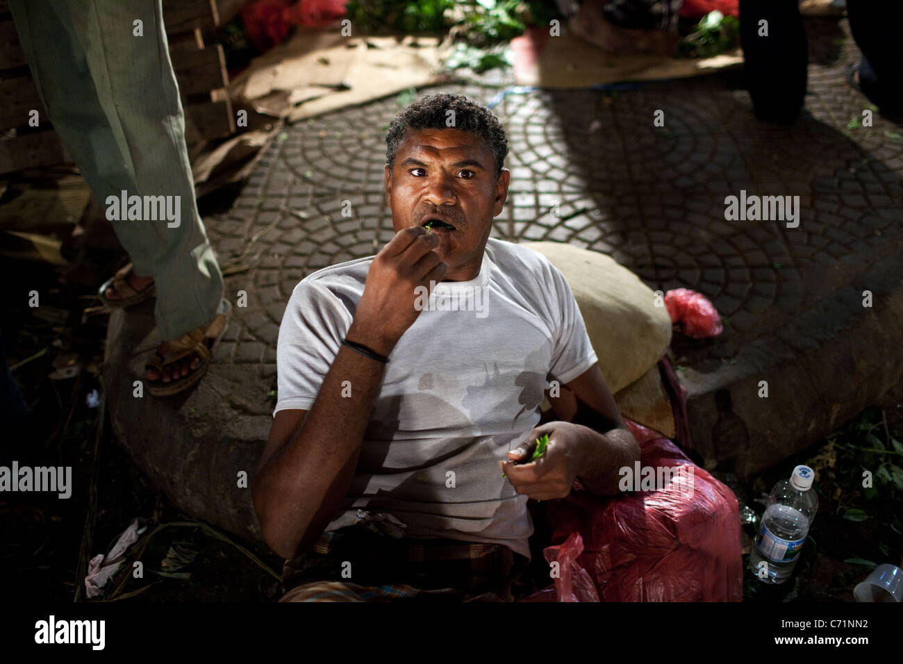 Un homme chews et vend le khat (QAT) au marché de nuit le khat à Aden, au Yémen. Banque D'Images