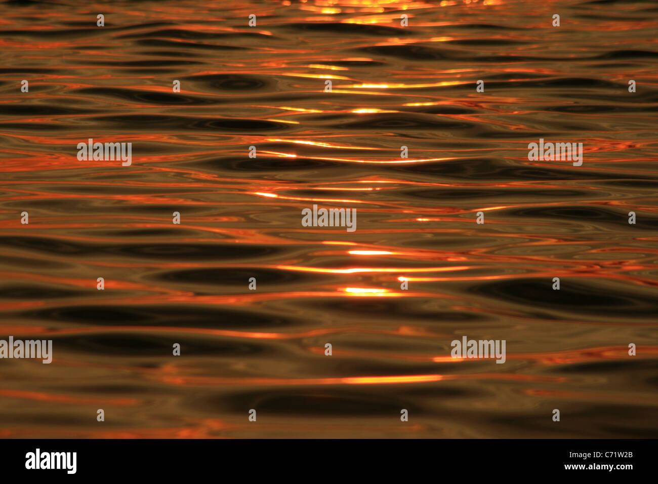 Coucher du soleil orange reflétée sur l'eau avec la texture d'ondulation Banque D'Images