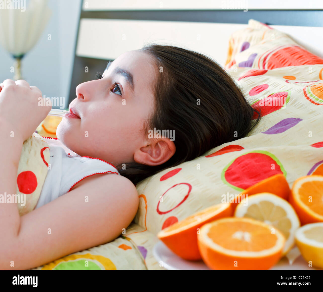 Petite fille avec un thermomètre au lit Banque D'Images