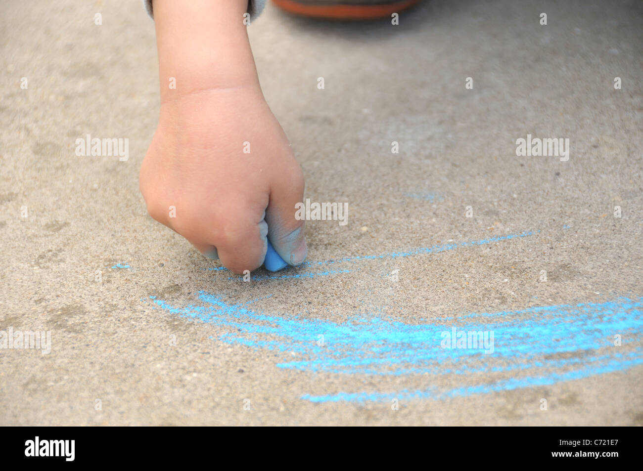 Un détail de la main d'un enfant tenant un crayon craie bleu dimensions piscine Banque D'Images