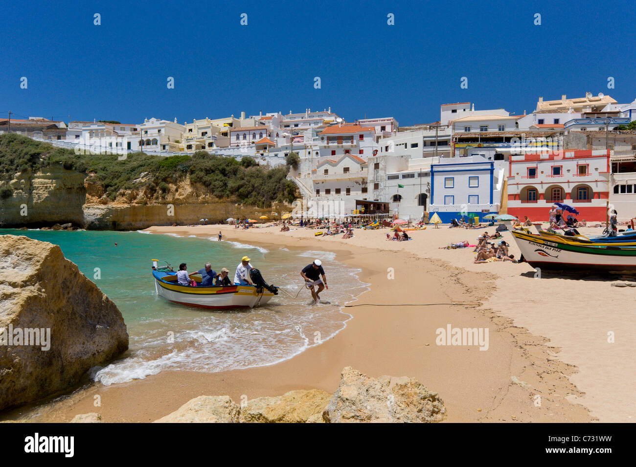 Le Portugal, l'Algarve, Praia do Carvoeiro ville et de la plage avec un bateau de pêche qui reviennent d'un voyage en bateau avec les touristes Banque D'Images