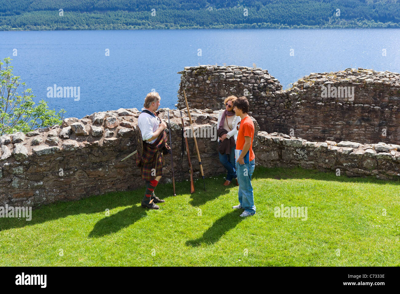 Les touristes parlant à l'un des re-enactment personnel dans les ruines d'Urquhart Castle sur le Loch Ness Près de Drumnadrochit, Ecosse, Royaume-Uni Banque D'Images
